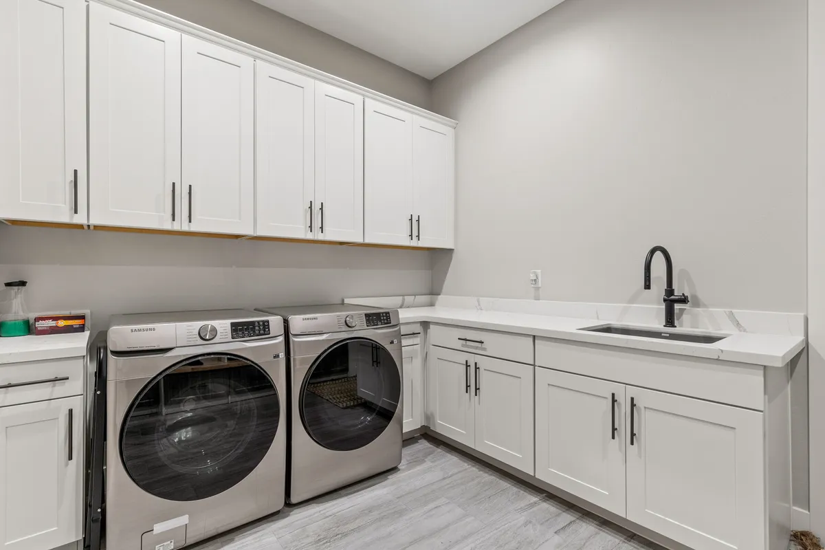 A well-organized laundry room with a washer and dryer, built-in sink, and ample cabinetry for storage. The space is bright and practical, perfect for handling laundry needs during longer stays.