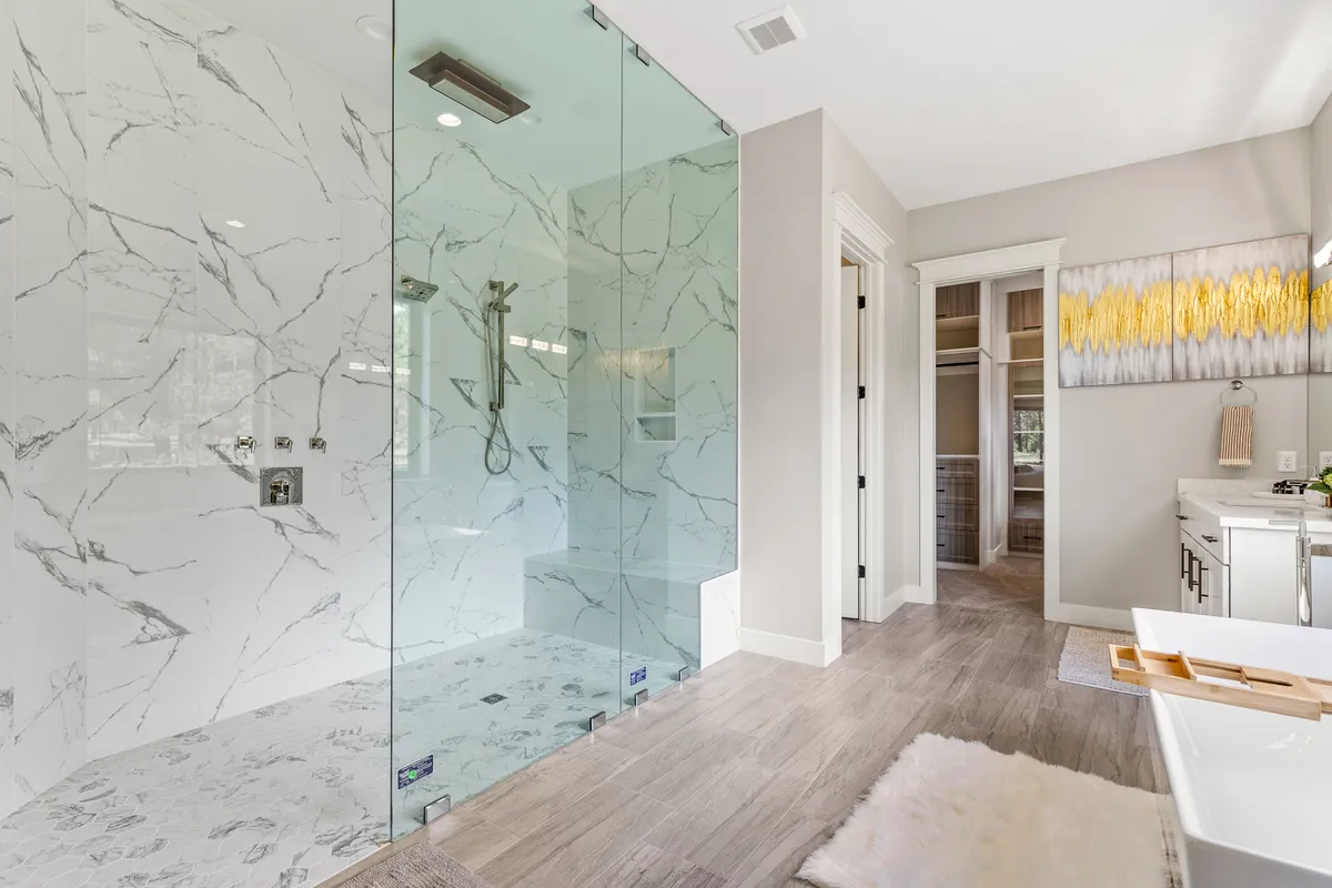 A luxurious spa-like bathroom featuring a freestanding bathtub, glass shower enclosure, marble walls, and a modern vanity. The space exudes tranquility and cleanliness, ideal for self-care routines and relaxation.