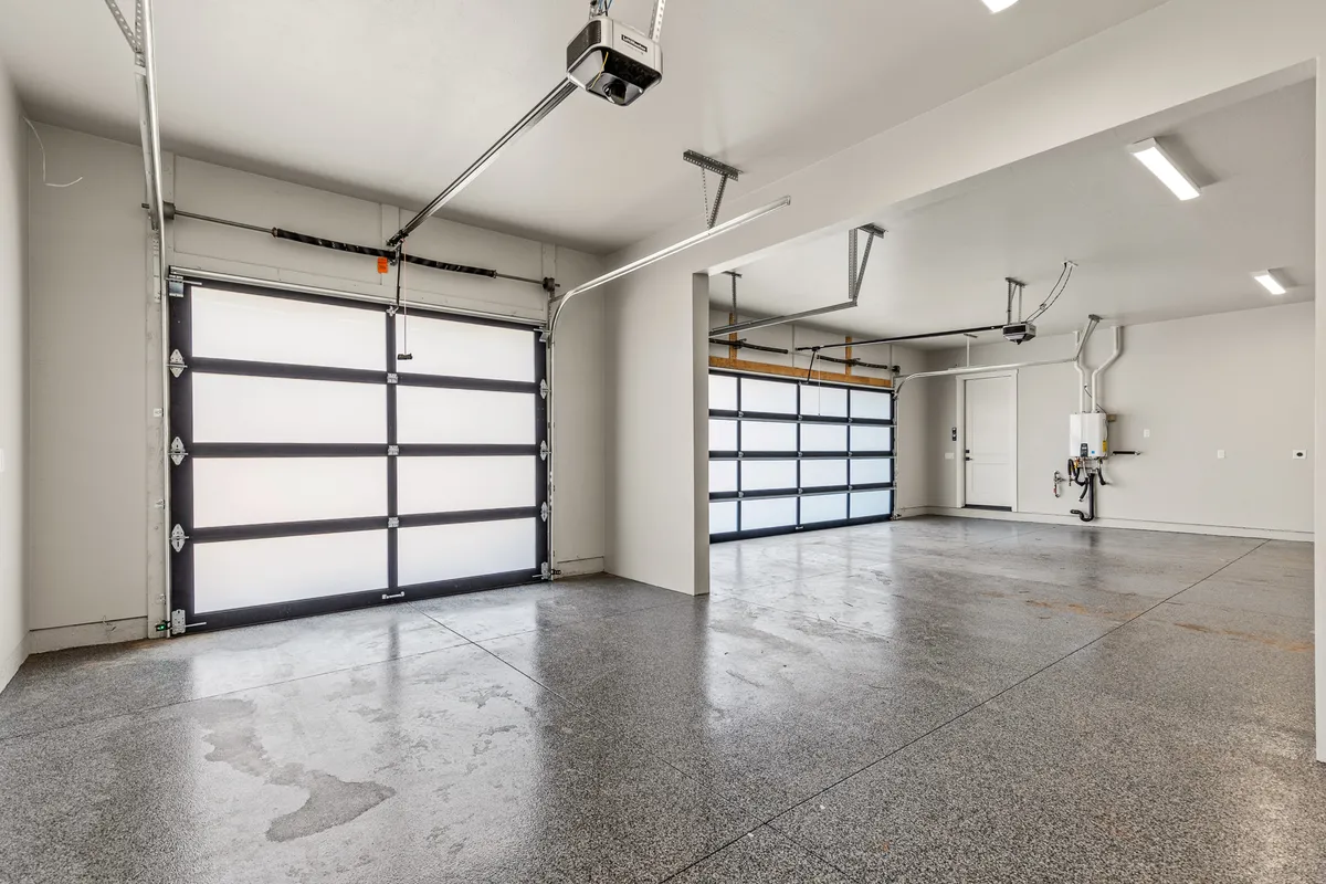 A spacious and tidy garage interior with polished concrete floors, garage doors, and a storage area suitable for vehicles and adventure gear. The organized space hints at convenience and readiness for exploration.